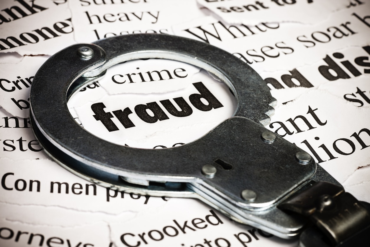 Tax Fraud 2 Handcuffs over newspaper with the word fraud